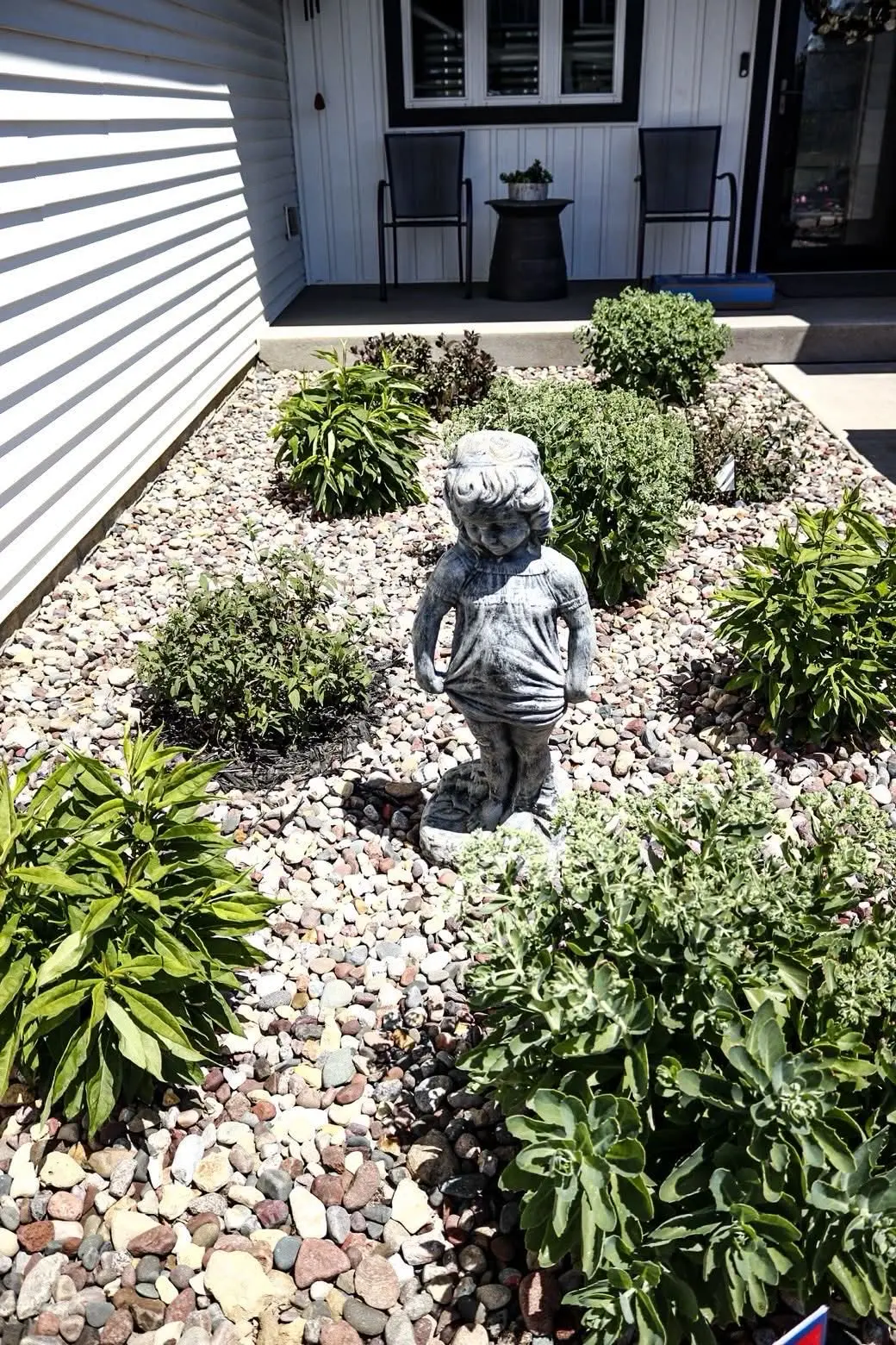 Landscaped garden bed with river stones and a statue